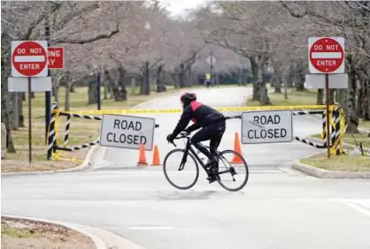  ?? Reuters ?? A man rides his bicycle in front of gates blocking the road leading to Haynes Point in East Potomac Park in Washington on Saturday.