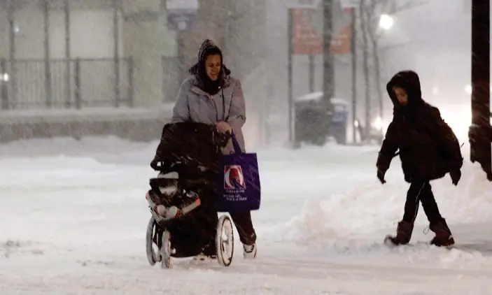  ?? Photograph: Christine Peterson/AP ?? A family walks up Front Street during a snow storm in Worcester, Massachuse­tts.