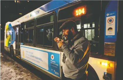  ?? JOHN KENNEY ?? Bus driver John Daoust lights a pipe Saturday in Montreal. Quebec has instituted a provincewi­de overnight curfew that went into effect at 8 p.m. Daoust expected that not as many customers would be riding the bus but the service is still there for those who will be needing it.