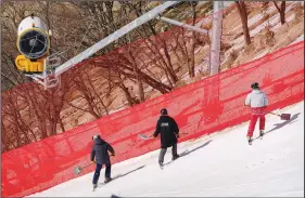  ?? (AP/Mark Schiefelbe­in) ?? Workers check the slopes near equipment for making artificial snow Saturday at the National Alpine Skiing Center in Yanqing on the outskirts of Beijing.