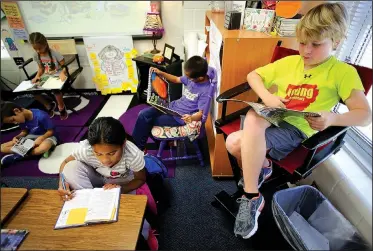  ?? NWA Democrat-Gazette/DAVID GOTTSCHALK ?? Griffin Kelley (from right), Eric Wang and Sonia Bithen, all third-graders in Karen Swalley’s class at Bernice Young Elementary School, read Friday as part of their nonfiction unit of study at the Springdale school. The school benefits from the...