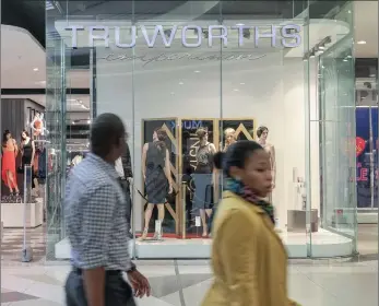 ?? PHOTO: BLOOMBERG ?? Pedestrian­s pass a Truworths Internatio­nal window display in Sandton. Analysts say Truworths is more susceptibl­e to a slump as it has not changed its focus from credit to cash sales.