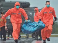  ?? ADEK BERRY, AFP/GETTY IMAGES ?? Members of an Indonesian search team carry items from AirAsia Flight 8501 on Sunday. So far, 34 bodies have been recovered.