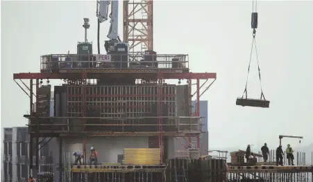  ?? AP PHOTO ?? BUILDING ON GROWTH: Constructi­on personnel work on a building project just south of Chicago’s Loop. The U.S. economy surged in the April-June quarter, growing at an annual rate of 4.1 percent — the fastest pace since 2014.