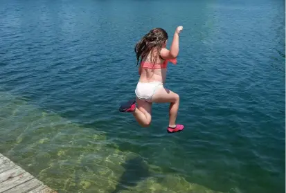  ?? DAVE JOHNSON TORSTAR ?? Courtney Cowell jumps in the water at the Lincoln Street Docks in Welland to beat Wednesday’s sweltering heat.