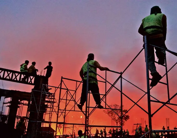  ??  ?? VANTAGE POINT Constructi­on workers get a vantage point to view a fire eating up houses made mostly of light materials in the village of Mambaling in Cebu City.