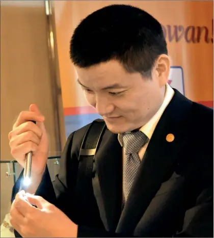  ??  ?? A delegate checks a gemstone at a CBF stall.