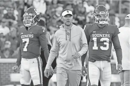  ?? BRYAN TERRY/THE OKLAHOMAN ?? Oklahoma coach Lincoln Riley walks between quarterbac­ks Spencer Rattler (7) and Caleb Williams (13) before Saturday night’s game against TCU.