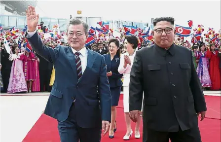 ?? — AP ?? Warm ties: Moon (left) waving while walking with Kim during a welcome ceremony at Sunan Internatio­nal Airport in Pyongyang, North Korea.