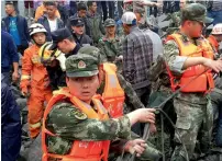  ?? — AFP ?? Military police and rescue workers are seen at the site of a landslide in Xinmo village, on Saturday.