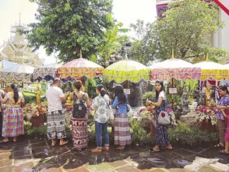  ??  ?? Locals and travelers line up to pay their respects and say their prayers at the Temple of the Reclining Buddha.