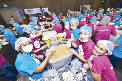  ??  ?? The volunteers continue with the mealpackin­g activity even after making it to the Guinness World Record (above). RAH USA PR and marketing specialist Madie Laing receives the certificat­ion from Guinness judge Philip Robertson (left).