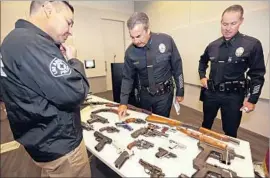  ?? Al Seib Los Angeles Times ?? LAPD CHIEF Charlie Beck, center, is briefed by Deputy Chief Justin Eisenberg, right, and Lt. Steve Embrich on some of the guns turned in at the annual buyback.