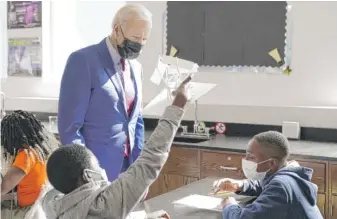  ?? MANUEL BALCE CENETA/AP ?? President Joe Biden stops to look at a student’s project as he tours Brookland Middle School on Friday in Washington. Biden has encouraged every school district to promote vaccines.