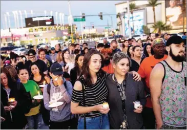  ?? DREW ANGERER/GETTY IMAGES/AFP ?? Mourners attend a candleligh­t vigil at the corner of Sahara Avenue and Las Vegas Boulevard for the victims of Sunday night’s mass shooting on Monday in Las Vegas, Nevada.