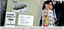  ??  ?? People walk past placards against a controvers­ial extraditio­n law proposal pasted on a wall near the Legislativ­e Council Complex in Hong Kong