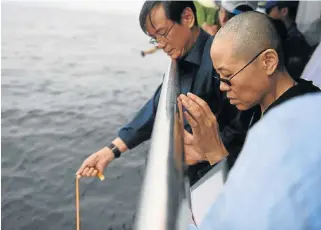  ?? /AFP Photo ?? Sorrowful times: This municipal handout photo shows Liu Xiaobo’s wife Liu Xia praying as Liu’s ashes are buried in the sea off Dalian on Saturday.