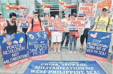  ??  ?? Environmen­tal activists display placards and streamers as they protest the continuing constructi­on of military bases across various reefs in the Spratlys Islands in West Philippine­s Sea during a rally in front of the Chinese Consulate in Makati city,...