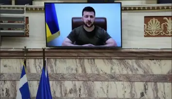  ?? Thanassis Stavrakis/Associated Press ?? Ukrainian President Volodymyr Zelenskyy, on the screen, addresses the Greek Parliament on Thursday in Athens, Greece. Mr. Zelenskyy called for more weapons to be sent from the West to Ukraine, tightened sanctions on Russia that would ban all Russian banks from doing business abroad and to bar Russian commercial ships from ports across the world.