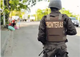  ?? ALONSO TENORIO. ?? Un oficial de la Policía de Fronteras realiza vigilancia en Cieneguita, Limón. A pocos metros varios vecinos conversan.