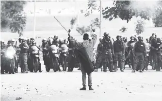  ?? AP ?? An antigovern­ment protester raises his violin before National Guards, as he yells not to shoot at protesters, creating a brief pause during clashes in Caracas, Venezuela, Thursday, May 18, 2017. In almost two months of unrest nationwide more than 40...