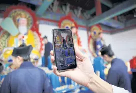  ??  ?? A priest live-streams Taoist priest Liang Xingyang, 41, as he moves memorial tablets.