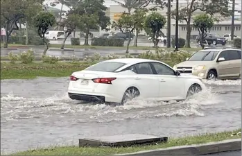  ?? LENIE LAWRENCE photo ?? Vehicles drive through floodwater­s on Dairy Road fronting U-Haul Moving & Storage of Kahului on Monday morning. Callers reported a couple of stranded vehicles and traffic lights blinking at intersecti­ons in Kahului as heavy rain fell throughout the day.