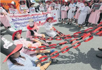  ?? WICHAN CHAROENKIA­TPAKUL ?? A group of female workers take part in an activity to mock indecent working conditions endured by pregnant workers during a rally in front of Government House to mark World Day for Decent Work 2018 and raise awareness about unfair employment and unsafe working conditions.
