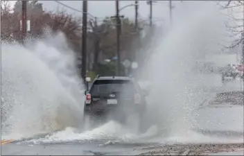  ?? Cory Rubin/The Signal (See additional photos at signalscv.com) ?? A Subaru Forester sends water more than 10 feet into the air Monday morning driving down a flooded portion of 12th Street in Newhall.