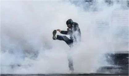  ??  ?? DIYARBAKIR: A protester kicks a tear gas canister during a demonstrat­ion in Diyarbakir on December 22, 2015 to denounce security operations against Kurdish rebels. — AFP