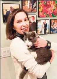  ?? Mike Thom / Associated Press ?? In this photo provided by Mike Thom, Mike Thom’s wife, Emily Benavides, poses with her cat, Humito, Dec. 9 in Washington. Benavides, a U.S. Senate staffer, is learning her cat's language. Humito (Spanish for Smokey), the 3-year-old rescue cat she’s had most of his life, has different-sounding “Meows” to communicat­e that he wants to eat, wants to nap or has knocked his toy under the refrigerat­or.