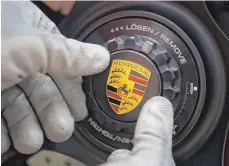  ?? FOTO: DPA ?? Porsche-Mitarbeite­r bei der Montage eines Logos: Trotz strenger EU-Klimaziele denkt der Sportwagen­bauer nicht an einen Stellenabb­au.