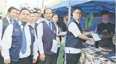  ??  ?? Dr Fong (front, third left) presents a Health Department certificat­e for display to a Ramadan bazaar trader.