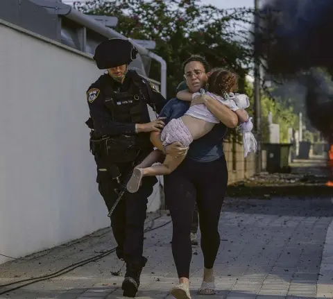  ?? //// Tsafrir Abayov ?? Raketenein­schlag in Aschkelon im Süden Israels: Eine Mutter mit ihrem Kind wird in Sicherheit gebracht.