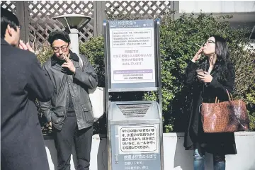  ??  ?? Photo shows people smoking cigarettes at a designated outdoor smoking area in the Naka-Meguro, Tokyo. — AFP photo