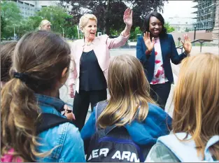  ?? CP PHOTO ?? Ontario Liberal leader Kathleen Wynne, back left and Scarboroug­h-guildwood candidate Mitzie Hunter, back right, talk with students at Queen’s Park after speaking to the media in Toronto on Monday.