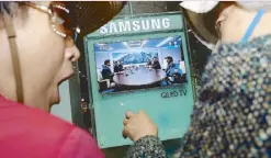  ?? AFP ?? A woman reacts to a companion while watching a screen showing news coverage of the inter-Korean summit meeting between South Korean President Moon Jae-in and North Korean leader Kim Jong-un, at a railway station in Seoul on Friday.