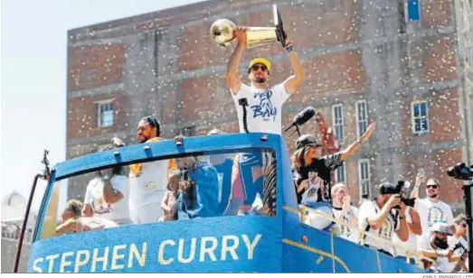  ?? JOHN G. MABANGLO / EFE ?? Stephen Curry levanta el trofeo de campeón durante el desfile de los Warriors.