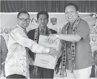  ??  ?? WETROM (kanan) menyampaik­an sumbangan mesin rumput kepada Ketua Kampung Mangin II Maranda Matunob.