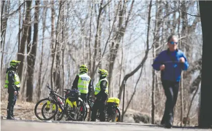  ?? CHRISTINNE MUSCHI ?? Police monitor foot traffic on Mount Royal to ensure people keep a distance from each other on Saturday. Big Brother watching is the price we pay to be allowed to continue walking, jogging and cycling during the present crisis, Allison Hanes writes.