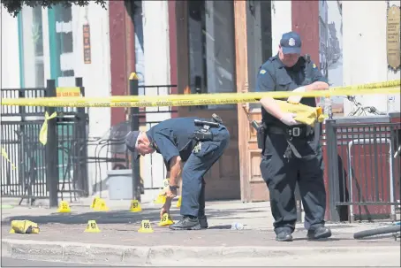  ?? JOHN MINCHILLO — THE ASSOCIATED PRESS ?? Authoritie­s retrieve evidence markers at the scene of an August 2019 mass shooting in Dayton, Ohio, a state with relatively lax gun-control laws.