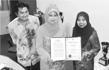  ??  ?? Fatimah (centre) gives Rosey (right) her certificat­e as SDC council member while Zufar Yadi looks on.