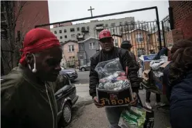  ?? Photograph: Wong Maye-E/AP ?? Surrounded by a few volunteers, a man carries food donations from St Stephen Outreach in the Brooklyn borough of New York on Friday 20 March.