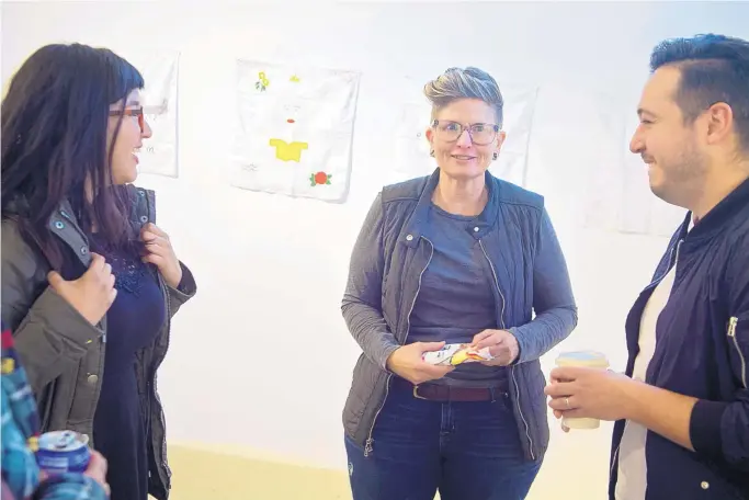  ?? MARLA BROSE/JOURNAL ?? Sheri Crider, center, owner of Downtown Albuquerqu­e’s Sanitary Tortilla Factory gallery, chats with artist Adriana Ortiz, left, and Luis Carlos Munoz, a coordinato­r with the Working Classrooms program, during the recent “The Story of Ourselves” exhibit at Sanitary Tortilla Factory.