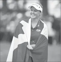  ?? Canadian Press photo ?? Canada's Brooke Henderson is wrapped in a Canadian flag as she celebrates her win at the CP Women's Open in Regina on Sunday.