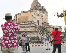  ?? GETTY IMAGES ?? Chinese tourists take pictures at a Buddhist temple in historic Chiang Mai, Thailand. The number of Chinese visitors to the Land of Smiles has tripled in the past five years to 8.8 million in 2016. That deluge of Chinese tourists has strained...