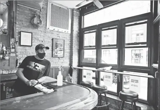  ?? CHRIS SWEDA/CHICAGO TRIBUNE ?? GMan Tavern manager Tom Cathcart waits Aug. 1 for carryout customers during the five-hour span on Saturdays when the bar operates.