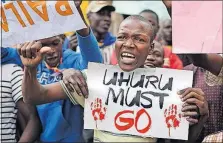  ?? [BEN CURTIS/THE ASSOCIATED PRESS] ?? A supporter of opposition leader Raila Odinga holds a poster referring to President Uhuru Kenyatta outside of the Supreme Court in downtown Nairobi, Kenya, on Wednesday.