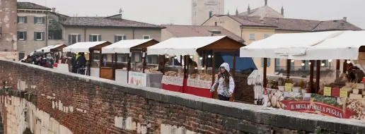  ??  ?? Tradizioni­Il mercatino a ponte Pietra e, nella foto piccola, la pista per il pattinaggi­o allestita a San Zeno (Foto Sartori)