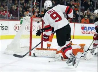  ?? TOM MIHALEK — THE ASSOCIATED PRESS ?? New Jersey’s Taylor Hall scores past prone Flyers goalie Michal Neuvirth to tie the game Tuesday night and send it into overtime at the Wells Fargo Center. The Devils won 5-4 via a shootout.